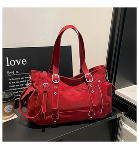 Detail of red utility tote bag featuring multiple metal buckles and side zipper pockets