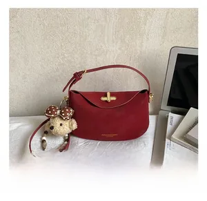 Detail of red leather saddle bag with gold clasp, teddy bear charm and pearl beads