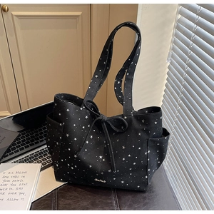 Detail of black star print tote bag with bow accent and side pocket in lifestyle setting