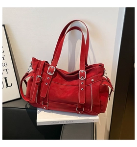 Detail of red leather tote bag showing silver metal buckles and decorative vertical straps