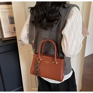 Brown leather crossbody bag detail with twin handles and stylish woven rope ornament