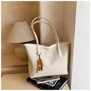 Close-up of cream white tote bag featuring embossed puppy patterns and wooden bead decor