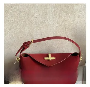 Detail of red tote bag featuring gold twist lock and cute plush bear charm with bow