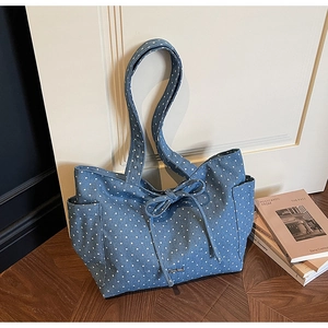 Detail of blue denim tote bag with white star pattern and stylish ribbon bow decoration