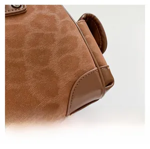 Détail de la texture en daim marron et passepoil en cuir lisse de qualité sur sac femme