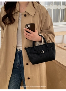 Gros plan d'un sac à main rétro en cuir noir avec boucle fer à cheval sur un modèle