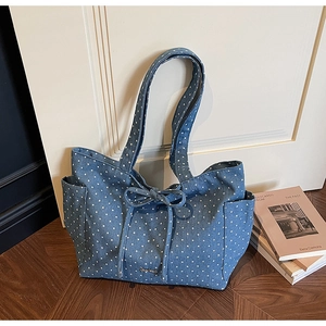 Close-up of blue denim star pattern tote bag with bow detail and functional side pockets