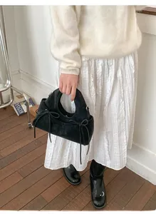 Minimalist black suede handbag with bow details shown in a casual lifestyle setting