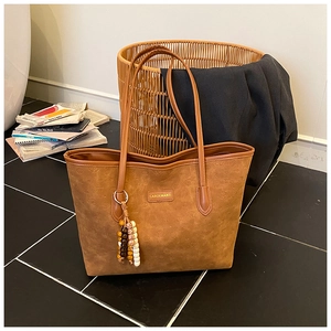Close-up of brown suede tote bag with embossed cartoon dogs and beaded pendant
