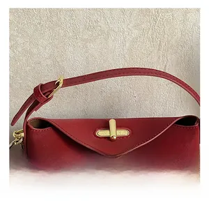 Detail view of the elegant red leather handbag featuring a refined gold metallic twist lock
