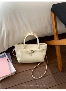 Détail d'un sac à main beige minimaliste avec nœud décoratif sur un parquet en bois chic