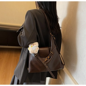 Détail du sac cabas en cuir marron vintage avec boucles dorées et breloque petit ours blanc