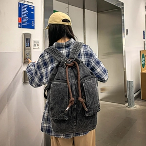 Detail of vintage black denim backpack with drawstring closure and brown rope accents