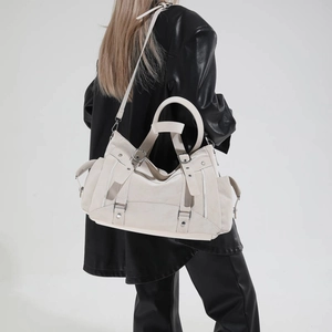 Close-up of a beige large-capacity tote with multi-zipper pockets and rivet details