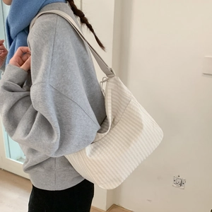 Close-up of beige striped canvas shoulder bag with wide adjustable strap for daily use