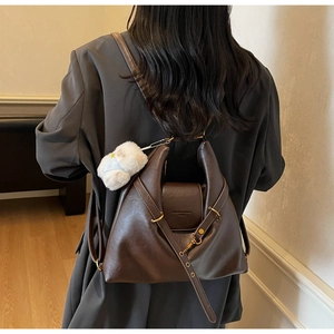 Détail d'un sac cabas rétro en cuir marron avec breloque ours sur le dos du mannequin