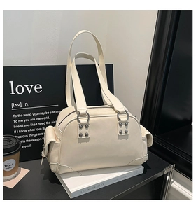 Détail du sac à main en cuir crème avec anneaux métalliques et poche latérale à rabat