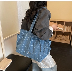 Detail view of blue canvas tote bag with white star pattern and decorative drawstring bow