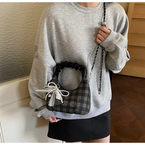 Detail of grey plaid cloud bag with lace bow and pearl chain worn by a model