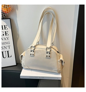 Détail du sac blanc cassé avec poches latérales magnétiques et accents de clous en métal
