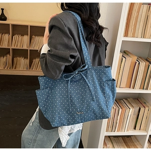 Detail of blue denim tote bag with star pattern, side pocket and bow drawstring accent