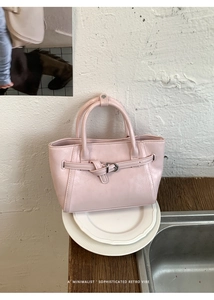 Sac à main rose minimaliste avec boucle décorative posé sur un plateau en céramique