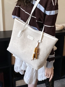 Minimalist beige faux leather tote bag with embossed logo and chic tassel detail