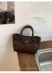 Gros plan de la texture en similicuir marron foncé et boucle en métal vintage du sac