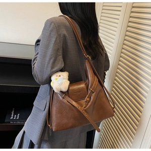 Vue latérale d'un sac cabas vintage marron avec logo embossé et breloque ours adorable