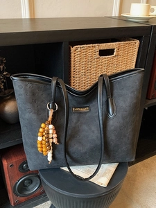 Minimalist black tote bag with embossed puppy patterns and elegant beaded pendant