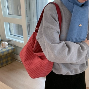 Detailed close-up of a red checkered crossbody bag showing large capacity and side pockets