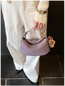 Detail of lavender leather handbag with silver twist lock and bear charm accessory