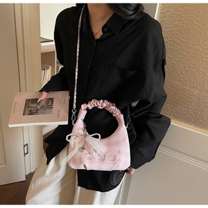 Close-up of pink checkered crossbody bag with lace bow, bear embroidery and chain strap