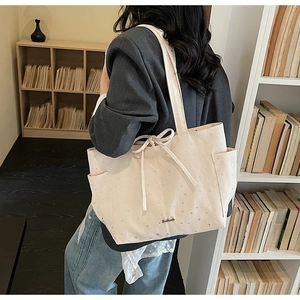 Close-up of cream canvas tote bag with star patterns and stylish drawstring bow closure