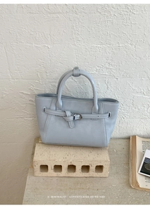 Gros plan d'un sac à main bleu clair minimaliste avec boucle sur décor de pierre