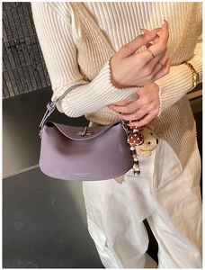 Detail view of purple matte leather handbag with metallic twist lock and cute charms
