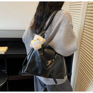 Détail du sac cabas en cuir noir avec un pendentif ours blanc et une bandoulière réglable