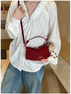 Detail of red crescent leather handbag with gold clasp and plush bear charm