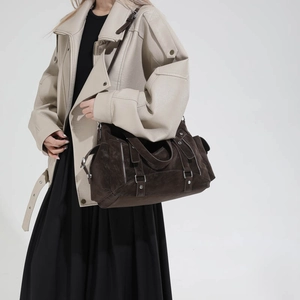Detail of a large brown suede tote bag featuring metallic hardware and zipper accents