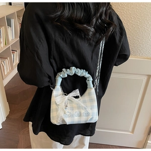 Close-up of light blue plaid bag with lace bow, bear embroidery and metal chain strap