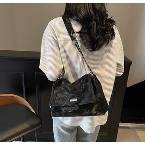 Close-up of black crossbody tote bag with chain strap and vintage leather texture