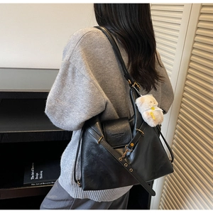 Détail d'un grand sac cabas noir en cuir avec pendentif ours en peluche blanc et boucles dorées