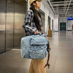 Detail of large denim travel bag with vintage wash and side braided rope decoration