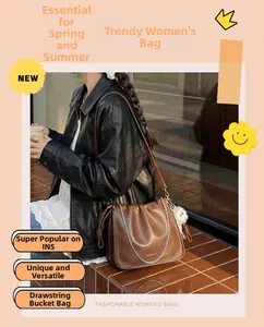 Detail of caramel leather drawstring bucket bag with gold chain strap and fur charm