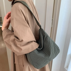 Detailed view of dark green plaid shoulder bag with lightweight fabric texture on model