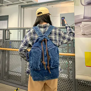 Detail of vintage blue denim backpack with dual front zipper pockets and drawstring closure