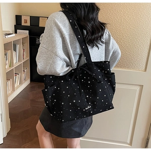 Detail of black canvas tote bag with white stars and handmade label in cozy room