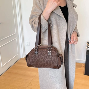 Détail d'un sac Boston imprimé léopard marron avec des rivets argentés et des anses en cuir