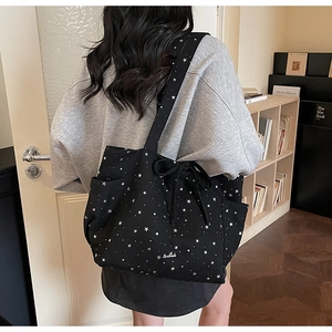 Black canvas tote bag with white star patterns and handmade embroidery shown on shoulder