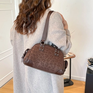 Détail du sac bandoulière léopard en daim avec finitions en cuir et rivets métalliques